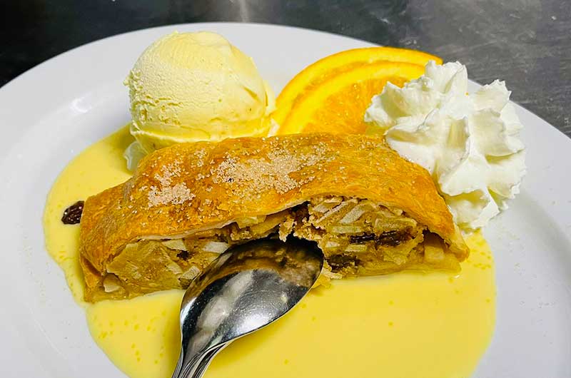 Apfelstrudel angerichtet mit 1 Kugel Vanilleeis und Sahne